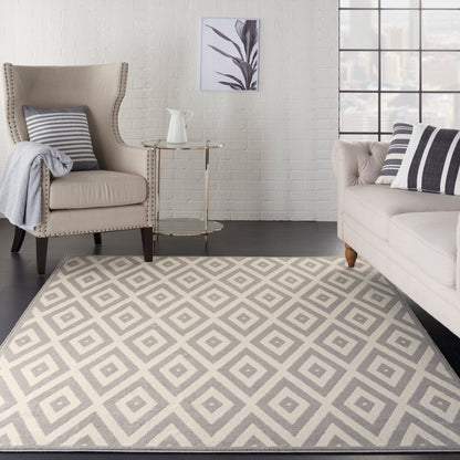 Neutral geometric diamond rug in gray and cream; modern living room with beige armchair, tufted sofa, striped cushions.