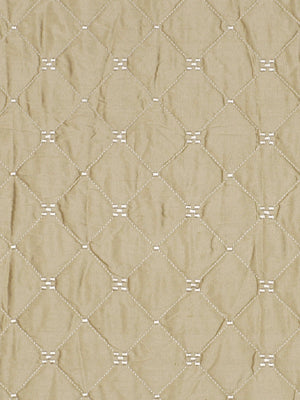 Beige quilted fabric with a diamond grid and tiny white stitch clusters at each intersection.