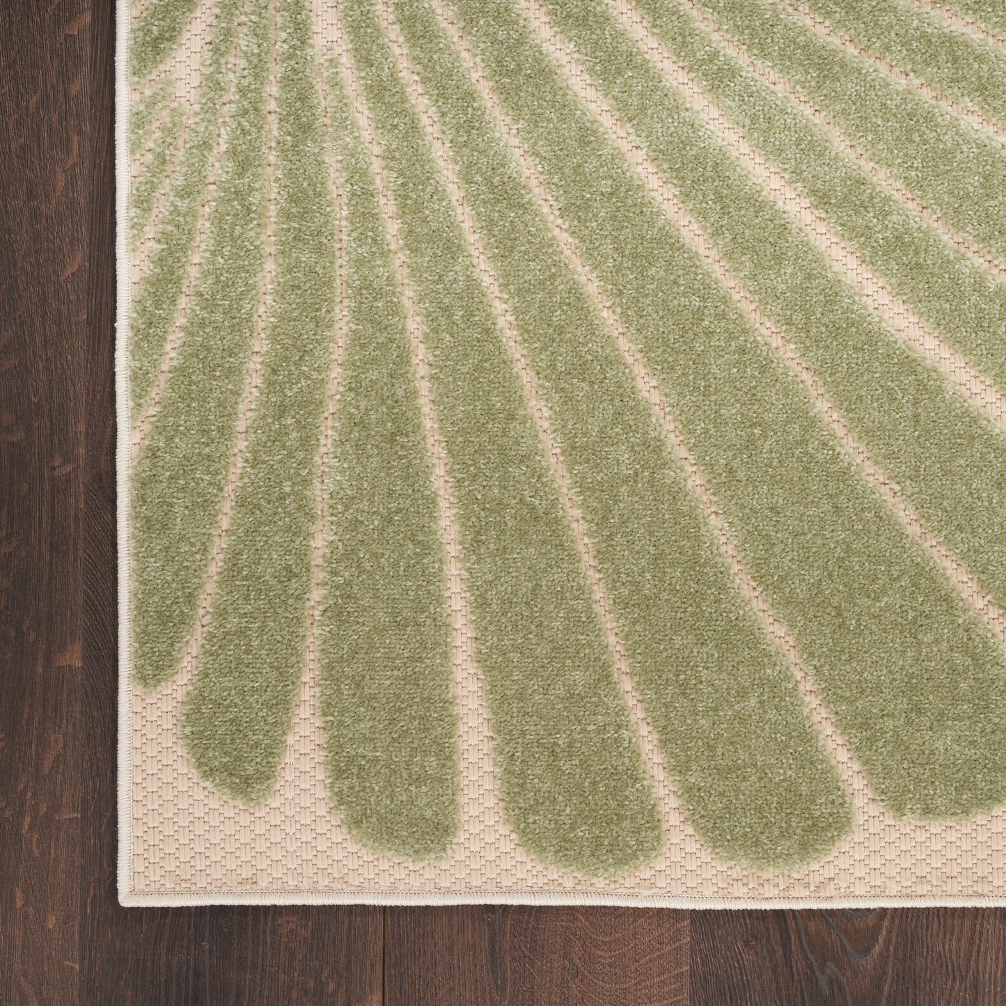 Olive-green tufted outdoor runner rug with cream petal-like stripes and white edge binding on dark wood floor.