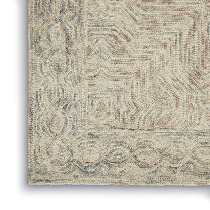 Corner of a plush cream and pale blue area rug with a geometric maze pattern and decorative border; tufted loop pile.