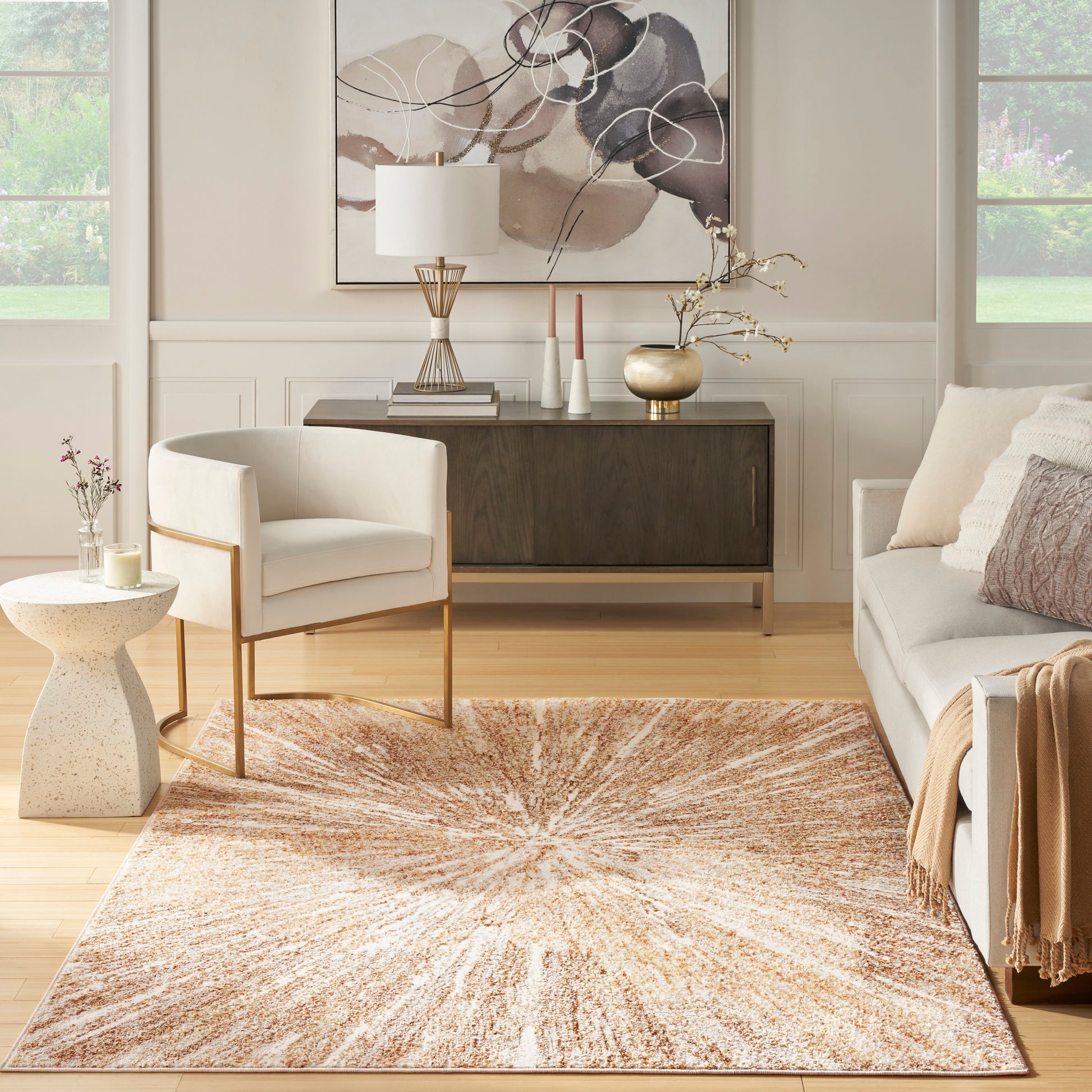 Sunburst-pattern woven area rug in warm orange-beige tones; contemporary living room with cream chair and neutral sofa.