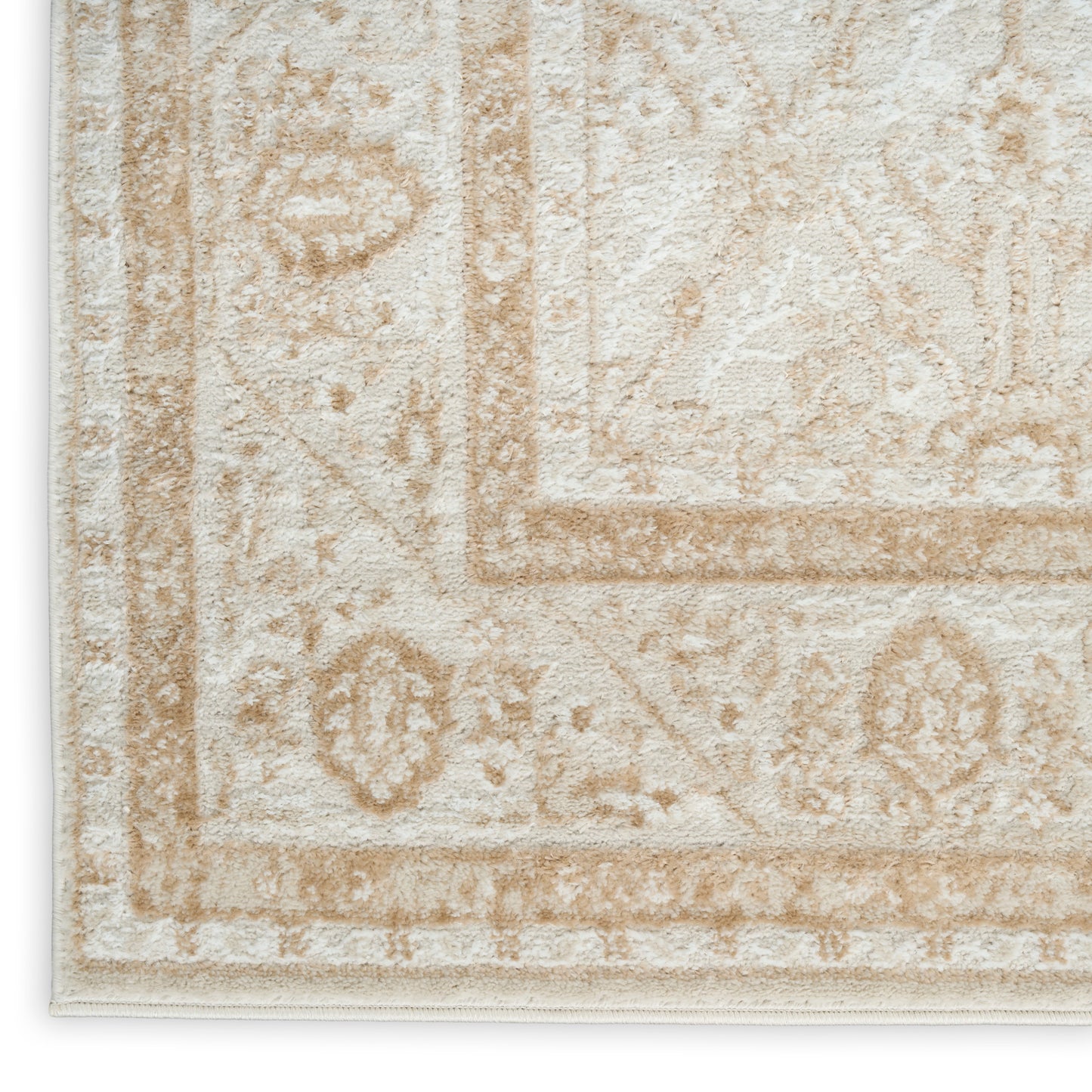Beige vintage-style area rug close-up with cream and tan floral border pattern and textured pile.