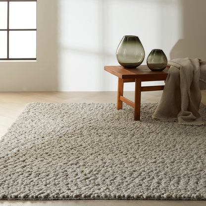 Beige shag rug on a wooden floor with a draped blanket.