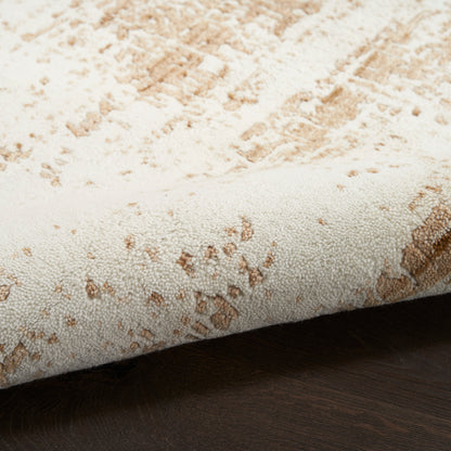 Cream and tan speckled area rug with plush pile, rolled edge on dark wooden floor.