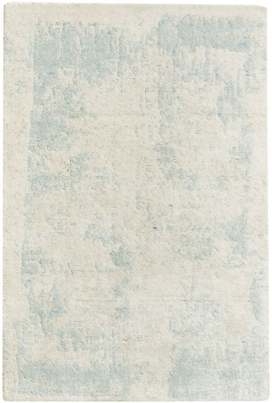 Rectangular area rug in cream with a pale blue abstract pattern and plush, soft pile.