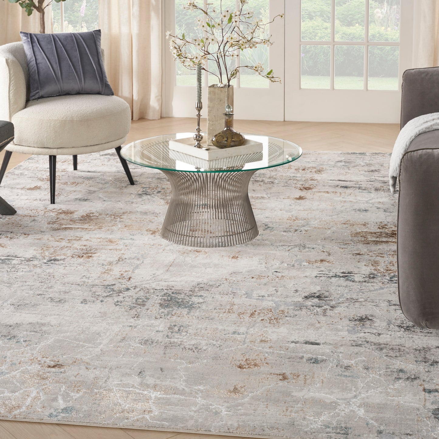 Modern rug in a living room with a beige chair and a gray sofa.