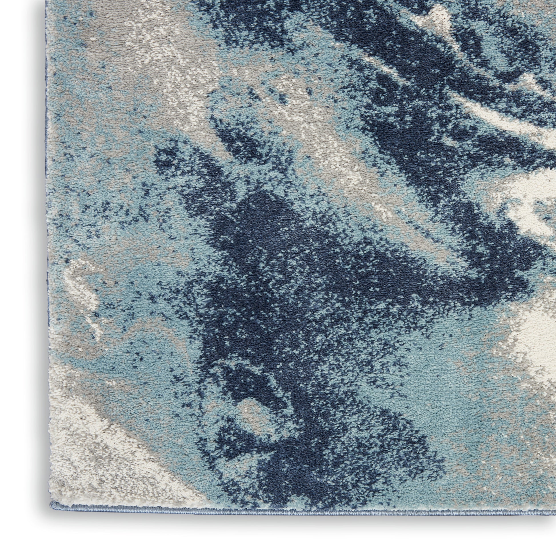 Rectangular abstract blue runner rug close-up with navy, light blue and cream tones; plush, textured floor covering.