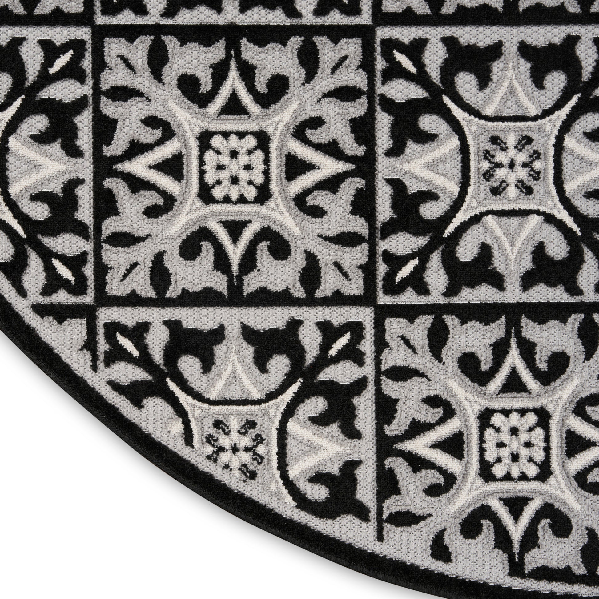 Round black and gray damask patterned rug with tile-like squares and ornate motifs.