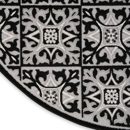Round black and gray damask patterned rug with tile-like squares and ornate motifs.