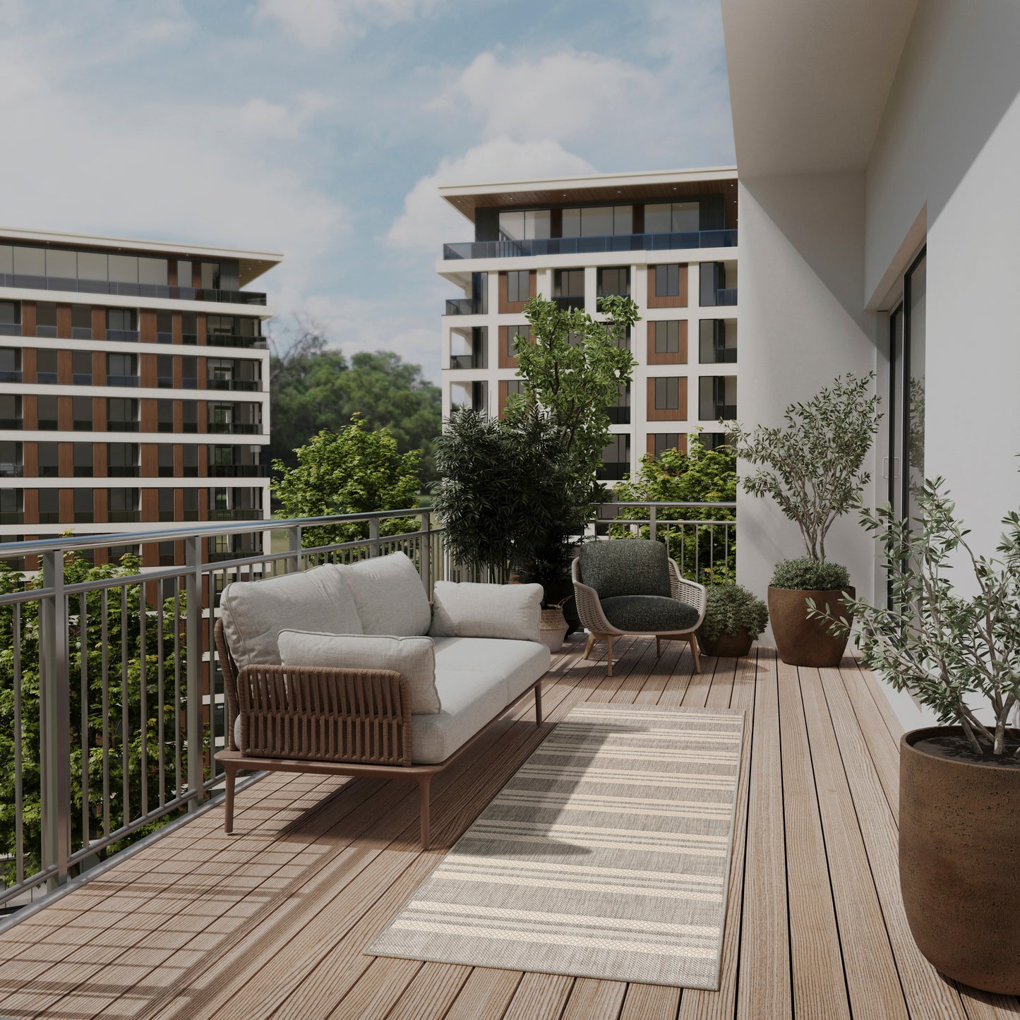 Sunlit balcony with light wicker sofa, gray cushions, rug, potted plants, and a dark lounge chair against modern buildings.