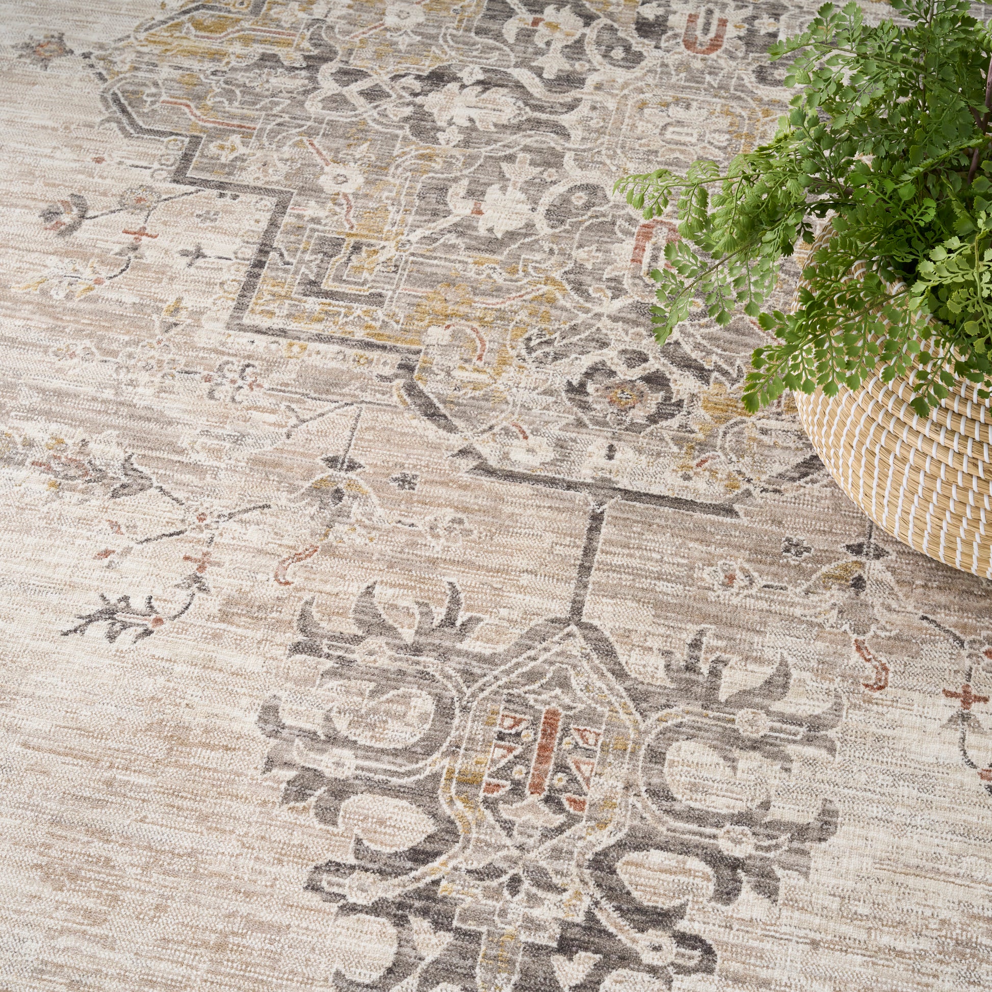 Muted beige oriental area rug with gray & tan medallion patterns; woven texture, beside a wicker plant basket.