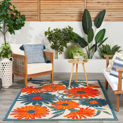 Outdoor 4' x 6' rug with an orange-blue floral pattern among green plants.