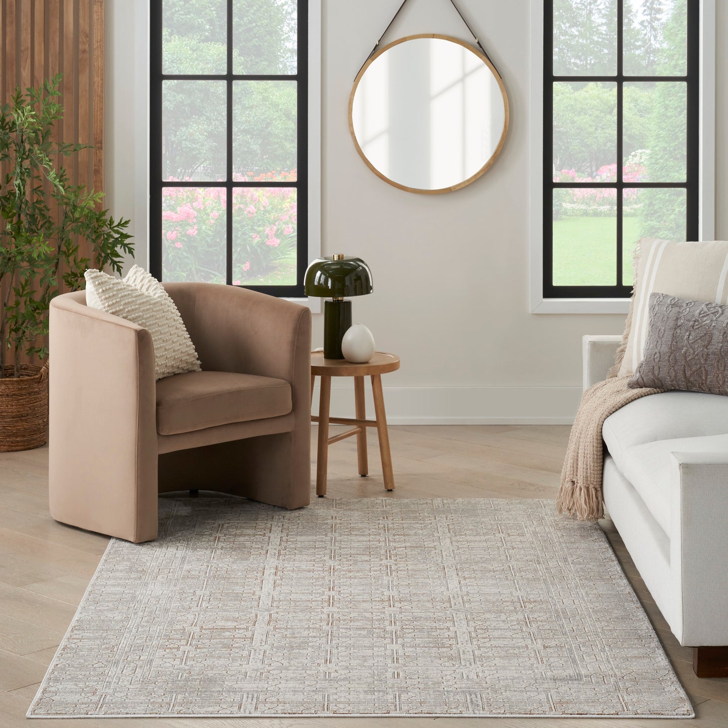 Beige curved armchair with plush fabric in a modern neutral living room, paired with a round wood side table and soft rug.