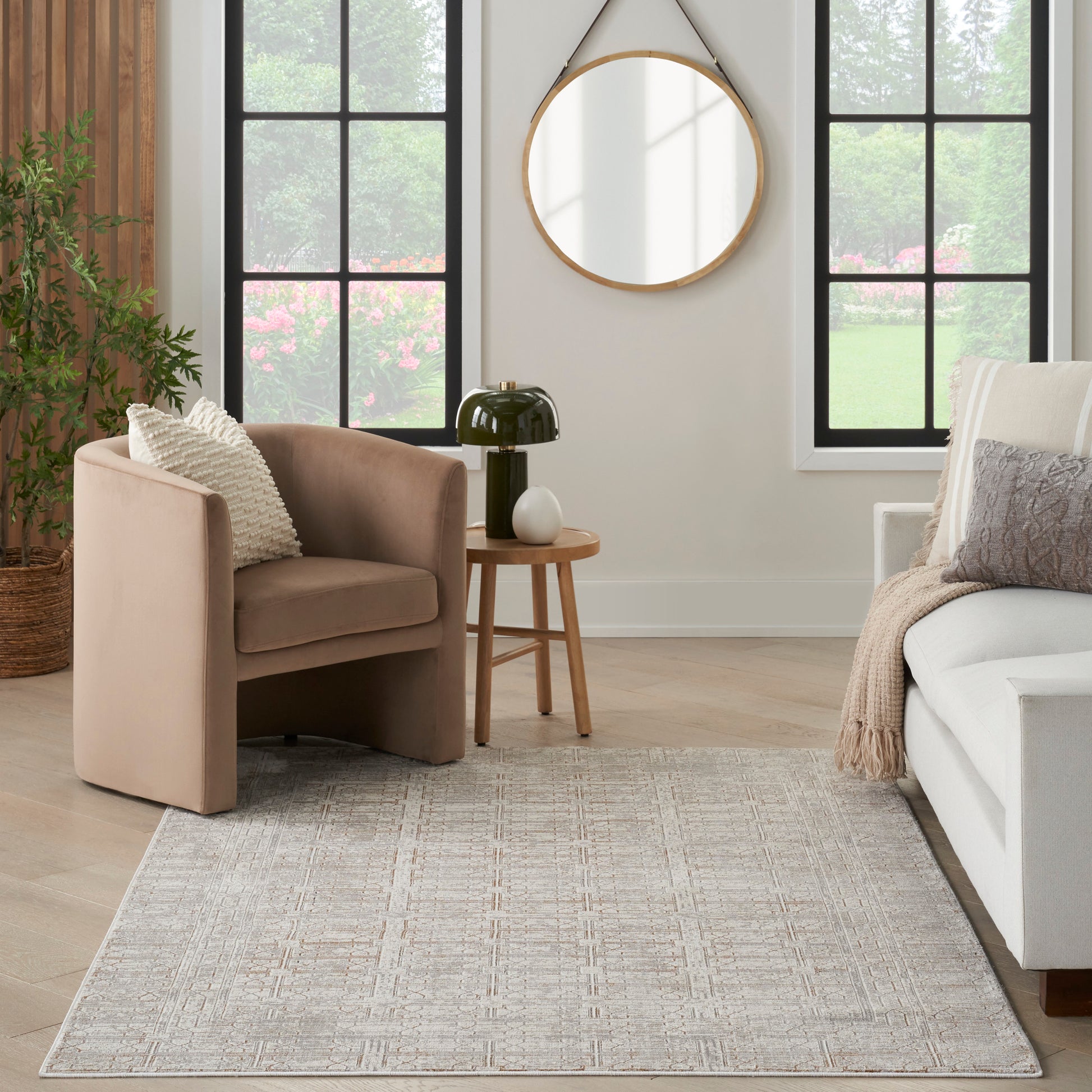 Beige curved armchair with plush fabric in a modern neutral living room, paired with a round wood side table and soft rug.