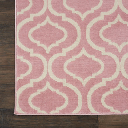 Pink area rug with white Moroccan trellis pattern on dark wood floor; soft textile, modern decor.