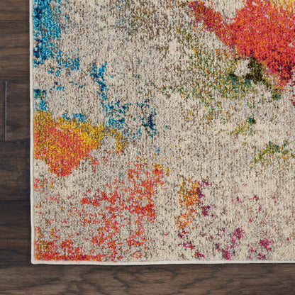 Beige abstract-pattern area rug with bright blue, pink, yellow, orange and green splashes on dark wooden floor.