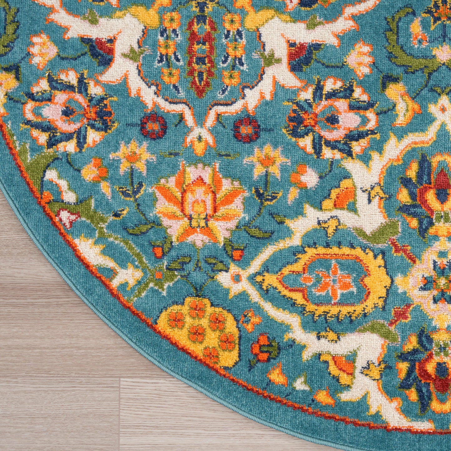 Turquoise oriental floral rug with vivid orange, yellow and cream blossoms; teal border on wood floor.