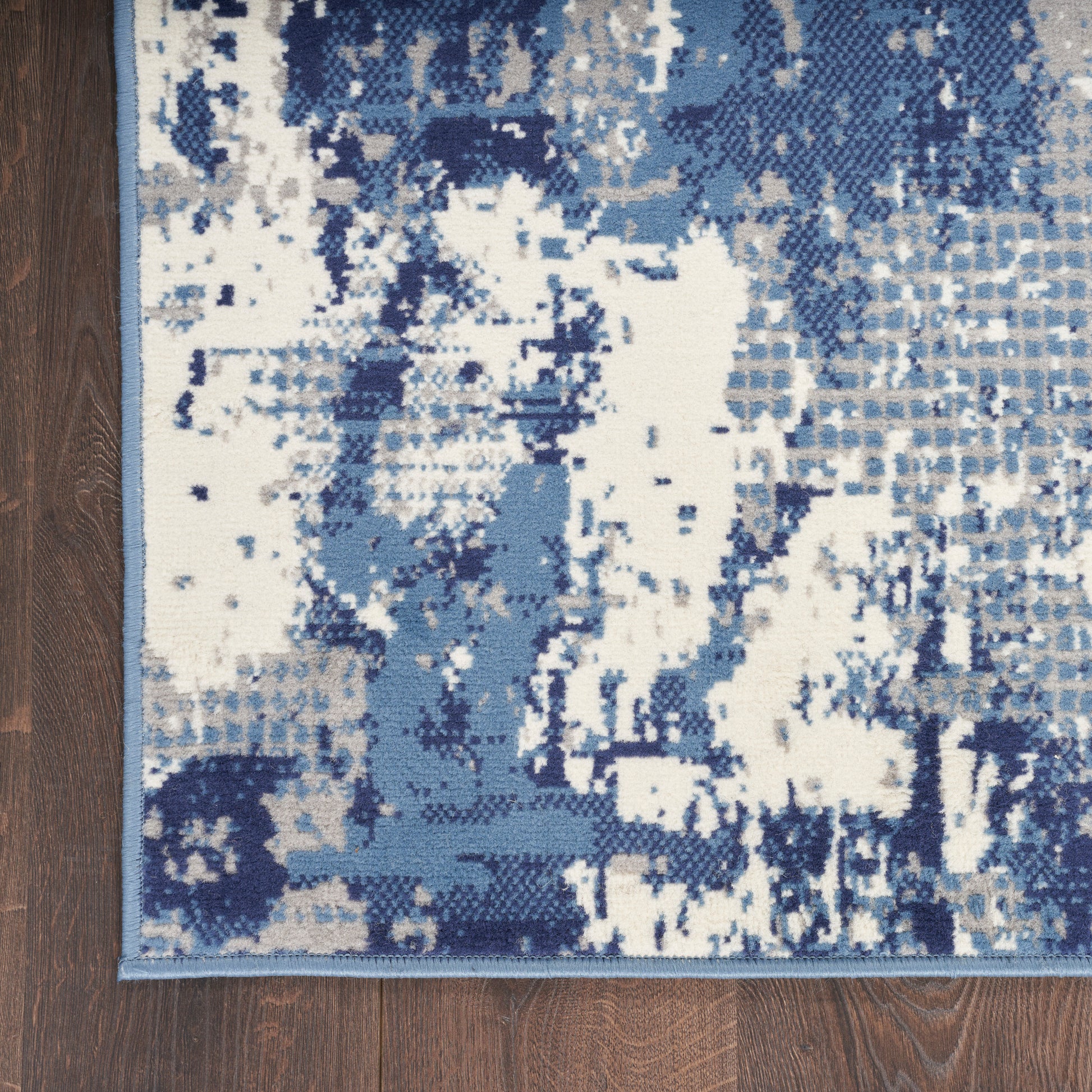 Abstract blue and white runner rug on wood floor with distressed geometric pattern and light blue border.