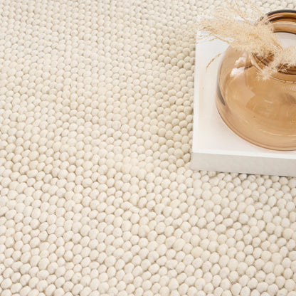 Beige looped carpet with a white tray holding a round tan ceramic vase and dried grasses.