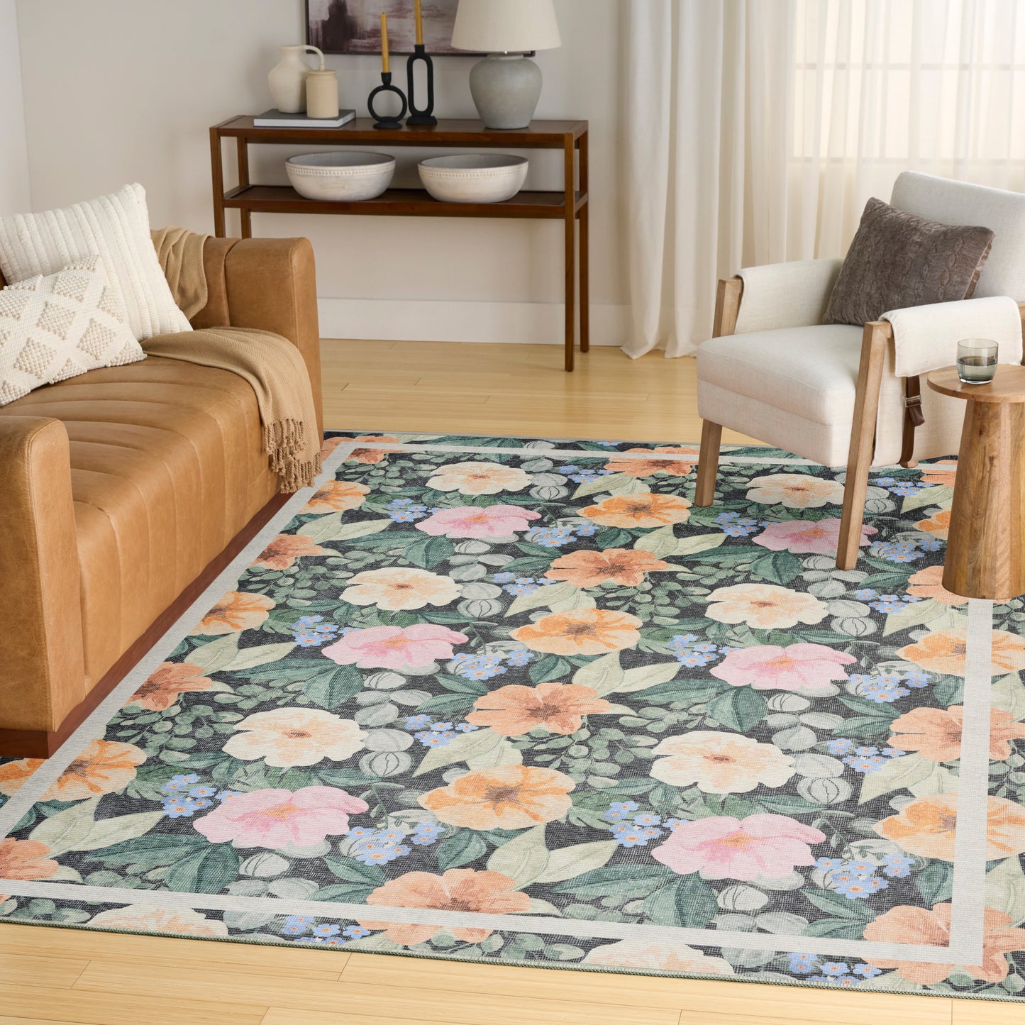 Floral area rug with green background featuring pink, peach and orange blooms, cream border; woven, in a modern-cozy living room.