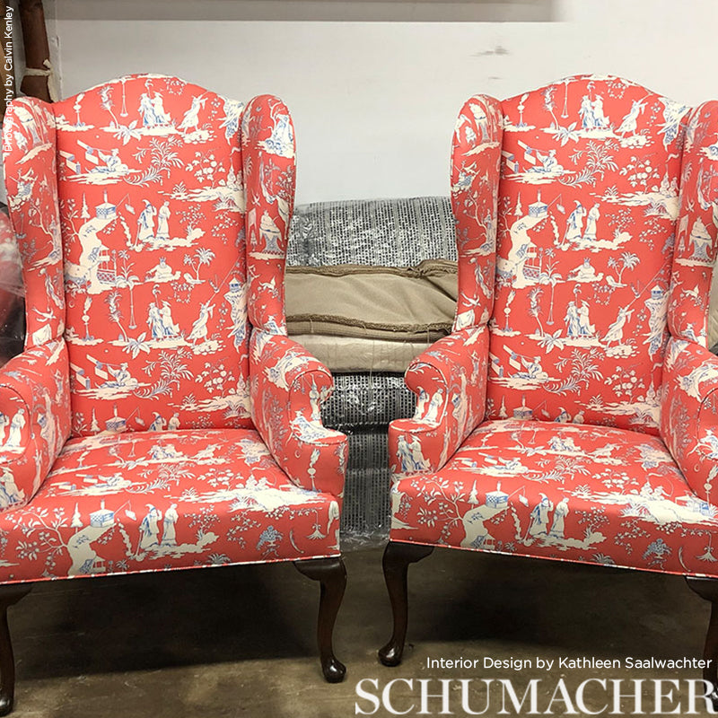 Pair of coral red wingback chairs with white toile print and dark wood cabriole legs.