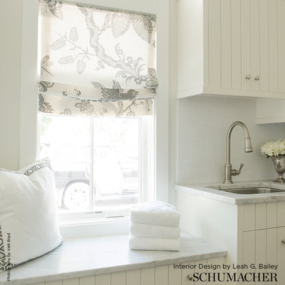 Bright kitchen window nook with marble sill, botanical roman shade, white cabinets, stainless sink, and towels.