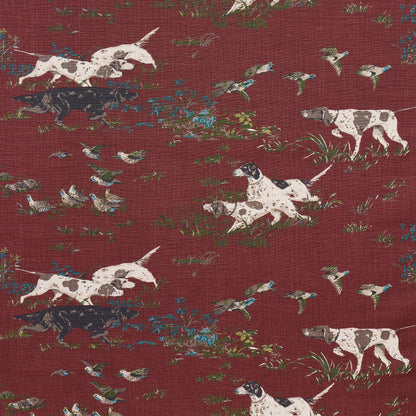 Burgundy fabric featuring white dogs with black patches, blue flowers and greenery in a vintage toile-style print.