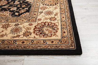 Beige Persian-style rug corner with floral medallions and a black border on a light wood floor.