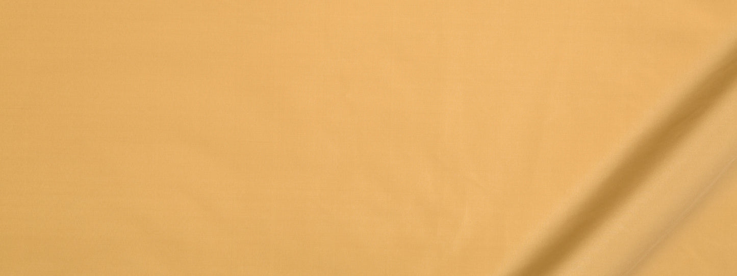 Close-up of warm beige fabric with diagonal seam and soft texture in a light orange tint.