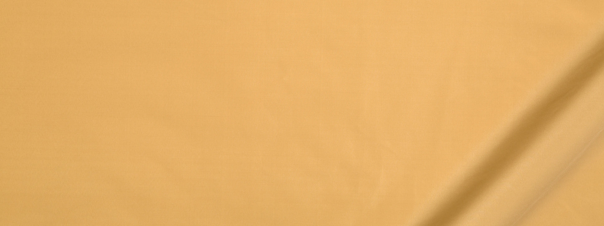 Close-up of warm beige fabric with diagonal seam and soft texture in a light orange tint.