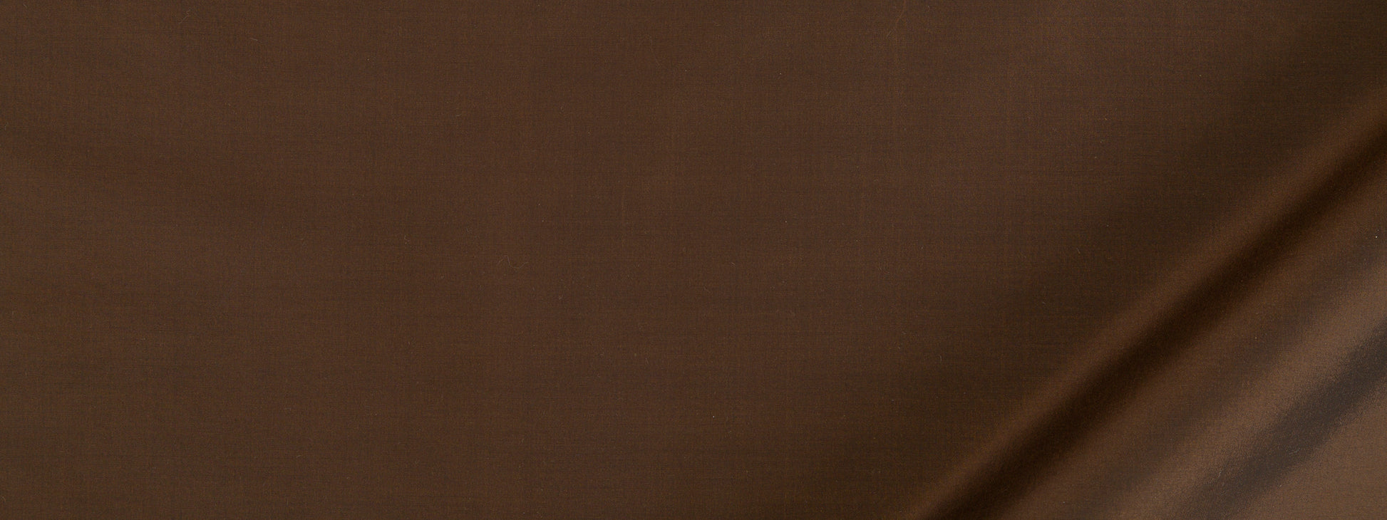 Close-up of warm brown textured fabric with a diagonal seam.