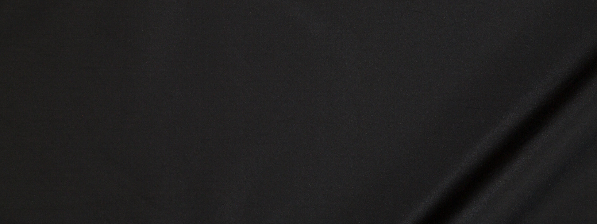 Close-up of dark black fabric with a subtle diagonal crease and smooth matte finish.