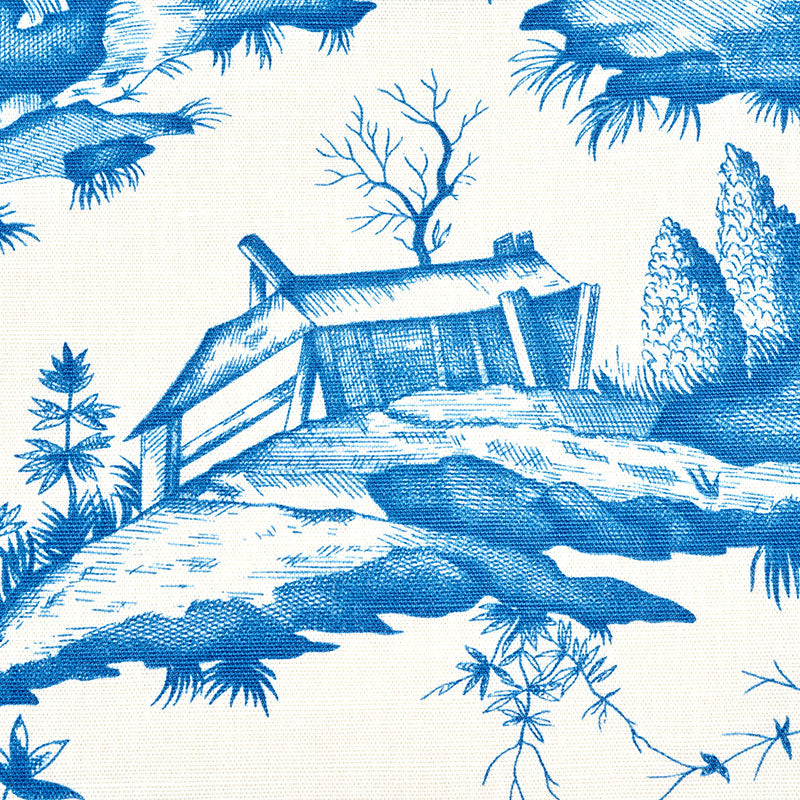 Blue toile print on cream fabric featuring a thatched-roof cottage, trees and rocky shoreline.