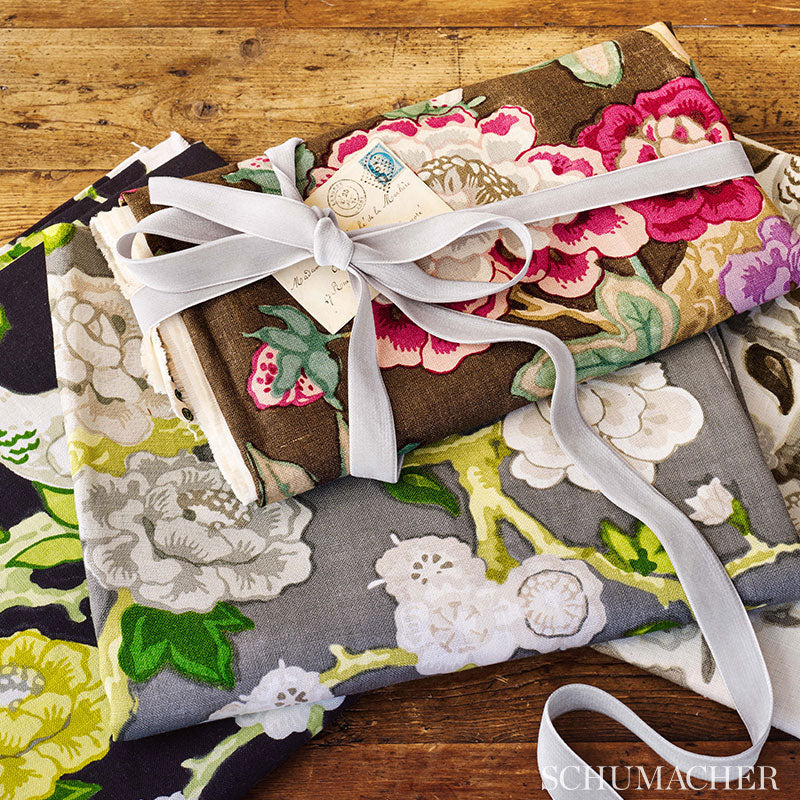 Floral fabric bundles in brown, pink and green tones tied with white ribbon on a rustic wooden surface.