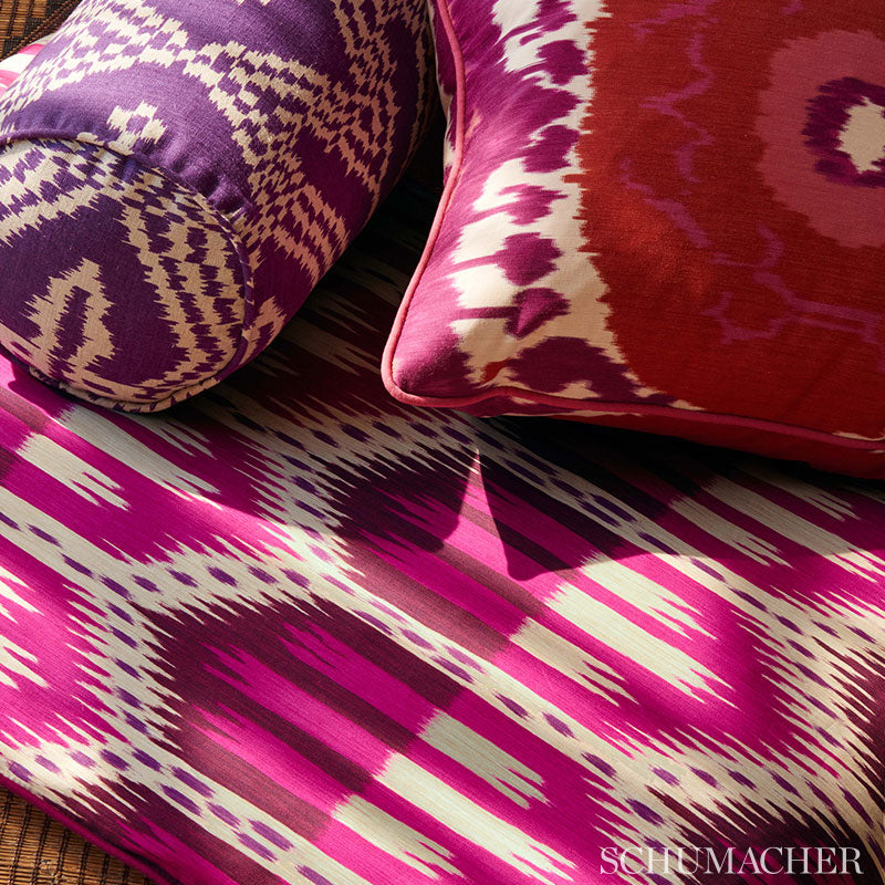 Purple and white ikat bolster with magenta cushion and pink piping on a bold pink-ikat textile.
