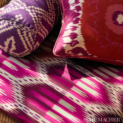 Purple and white ikat bolster with magenta cushion and pink piping on a bold pink-ikat textile.