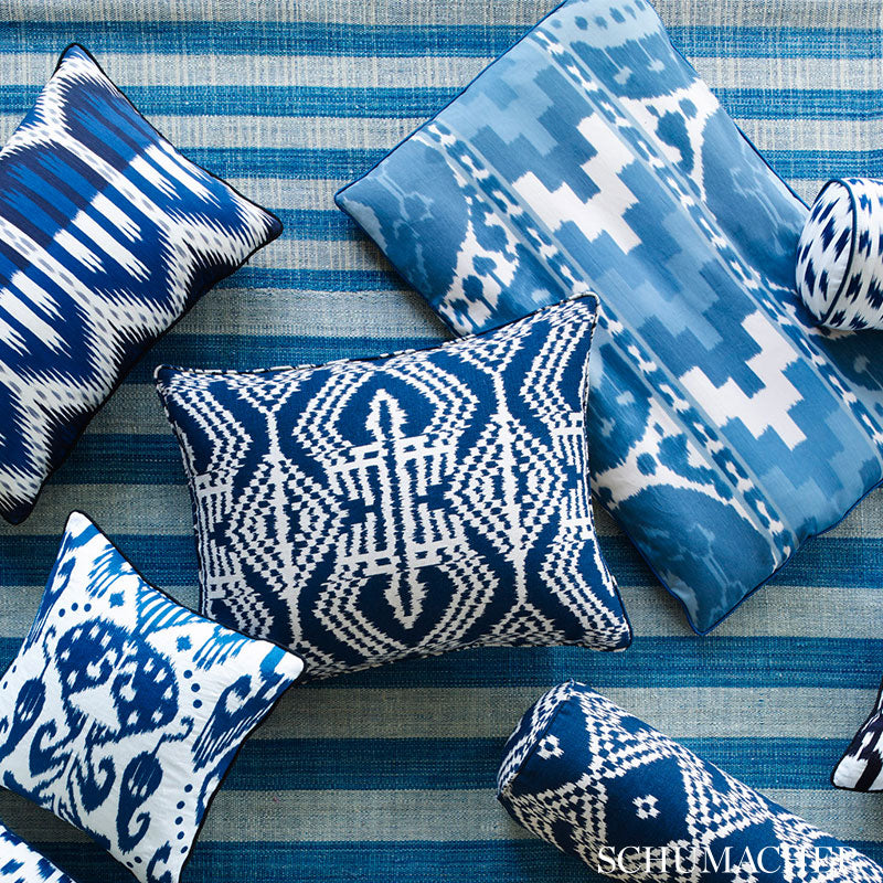 Blue and white geometric throw pillows (ikat/abstract patterns) on a striped blue rug.