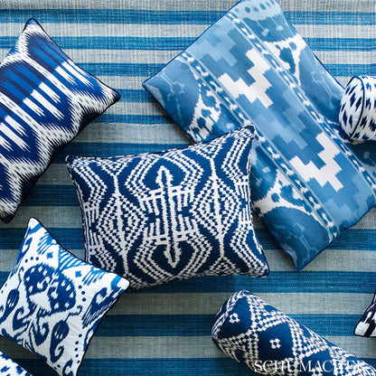 Blue and white geometric throw pillows (ikat/abstract patterns) on a striped blue rug.