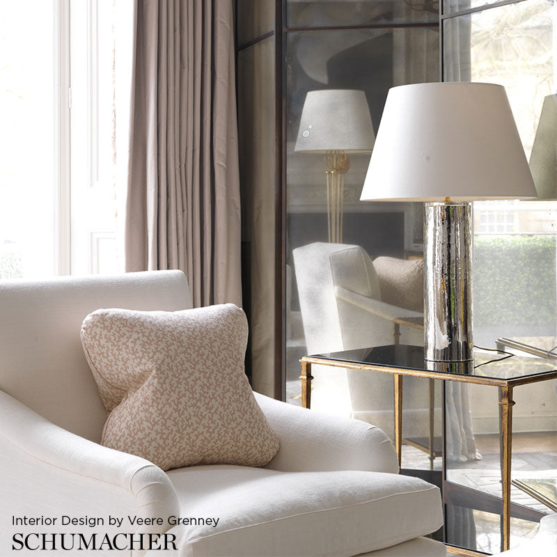Cream sofa with a patterned throw pillow, glass-and-gold side table, and chrome lamp with white shade in a bright living room.