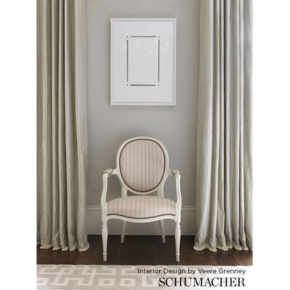 Cream oval-back Bergère chair with striped beige upholstery and carved frame, set in a neutral living room with gray walls.
