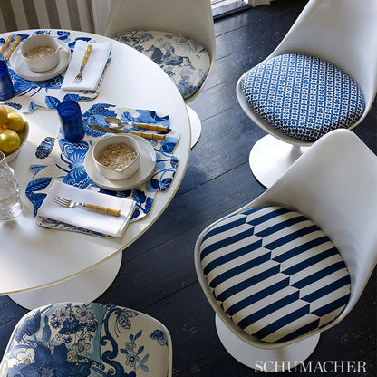 White round table with blue-and-white placemats, bowls of oats, lemons, and tulip chairs with striped floral cushions.