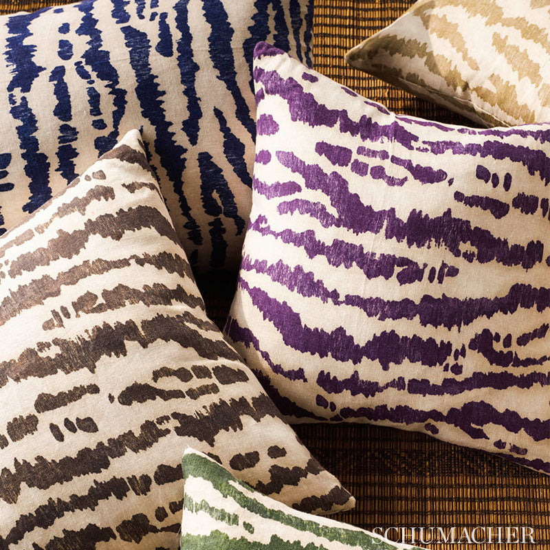 Decorative zebra-print throw pillows in navy, purple and brown on cream/white fabrics, placed on a woven rattan surface.