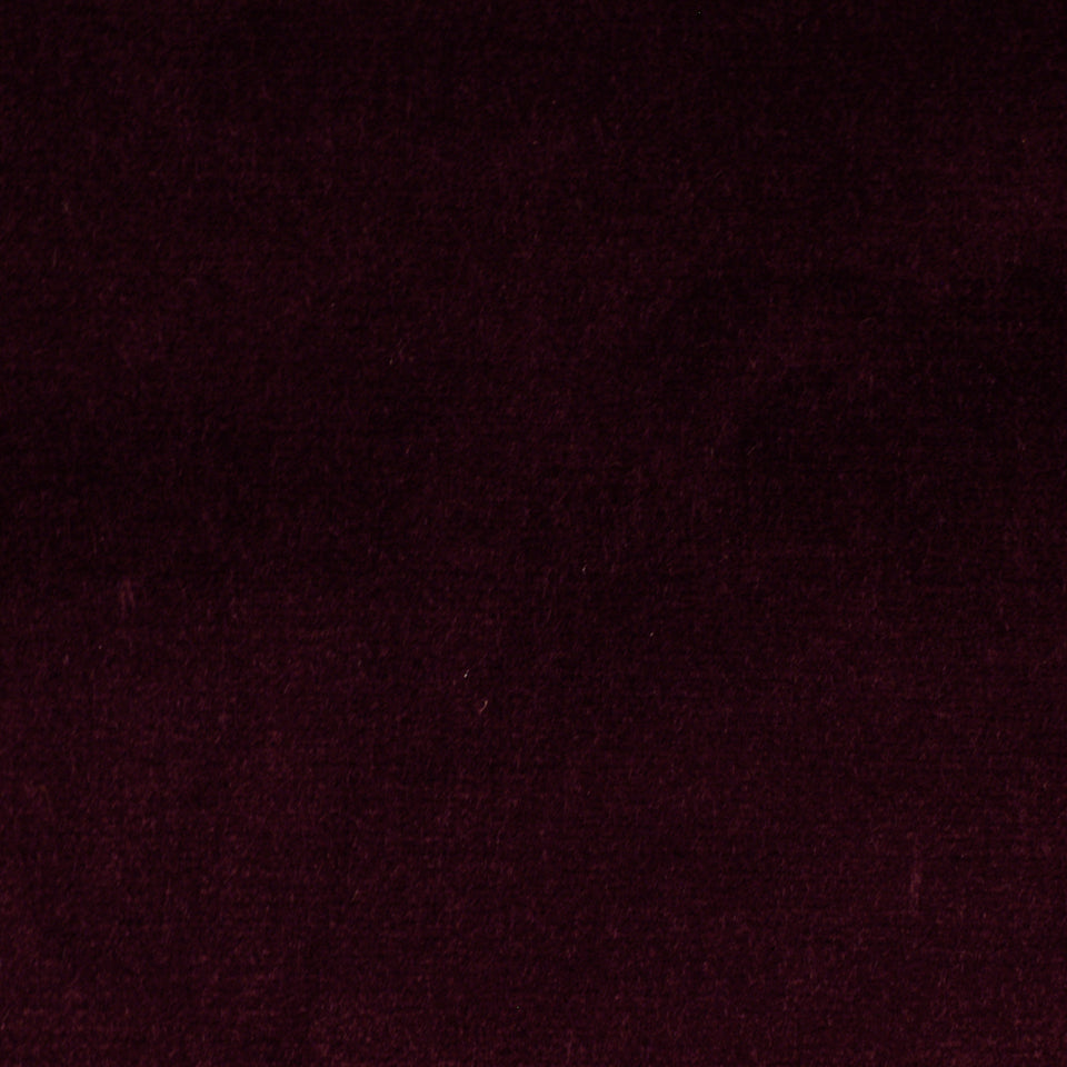 Close-up of burgundy velvet upholstery fabric with rich nap and deep red color.