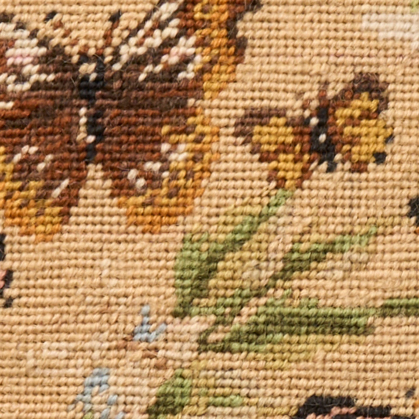 Beige woven tapestry close-up with a brown butterfly motif and yellow flowers on green leaves.