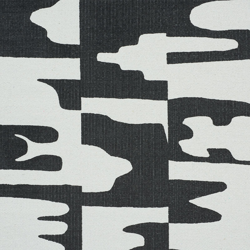 Abstract black and white canvas textile with irregular white shapes on a dark background, a modern geometric pattern.