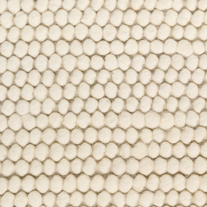 Cream boucle rug close-up with soft rounded tufts forming a dense, textured grid.