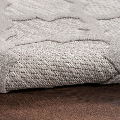 Light gray plush rug with raised cloud-like pattern and braided border on dark wood floor.