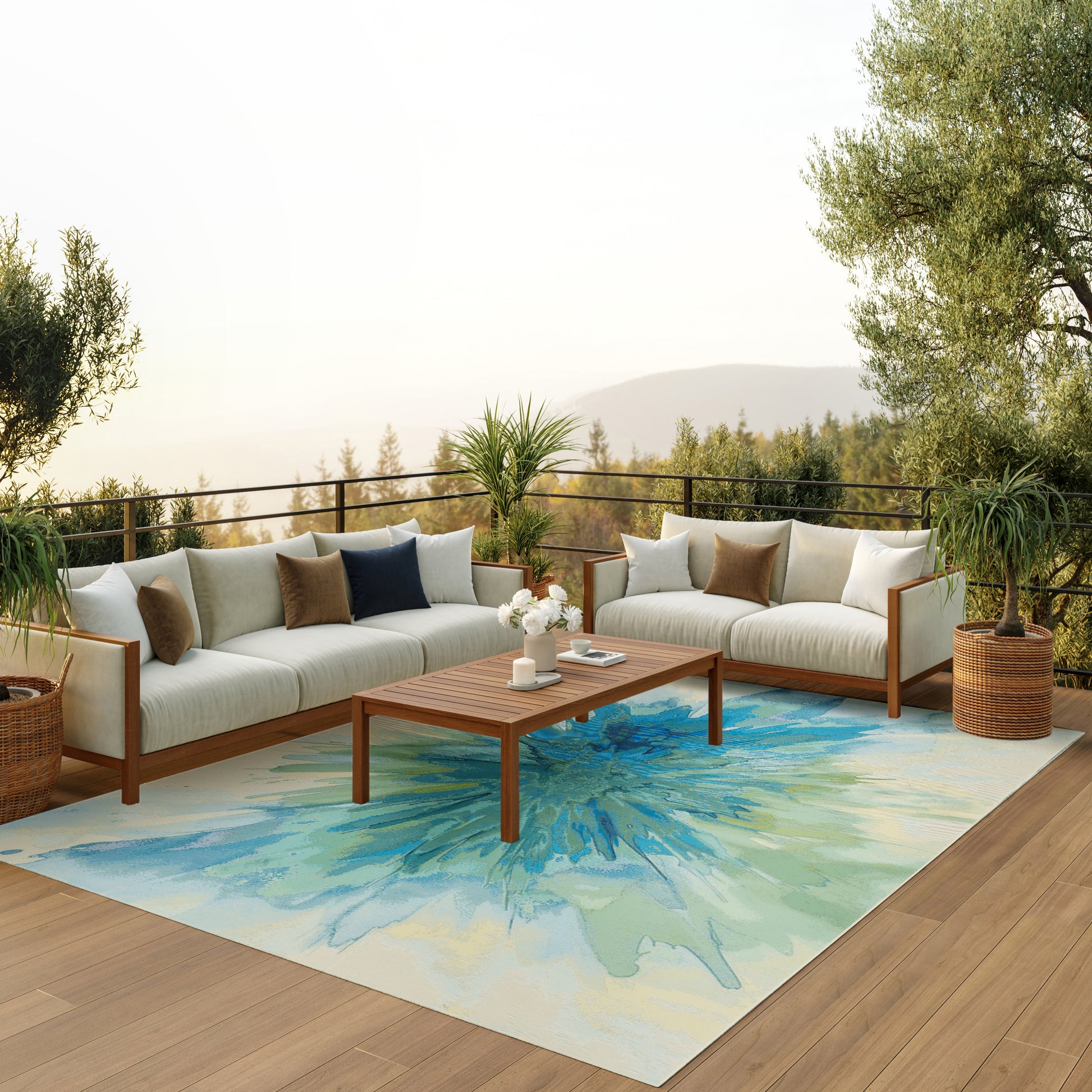 Outdoor wooden-frame sectional with beige cushions on a deck, blue-green rug, coffee table, potted plants, hillside backdrop.