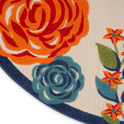 Round floral rug with bold orange and teal flowers, beige background, navy border and woven texture.