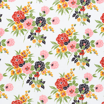 Bright floral fabric print with red, pink and dark purple blooms, yellow blossoms and green leaves on white fabric.
